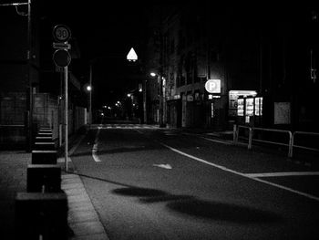 Empty road along buildings at night