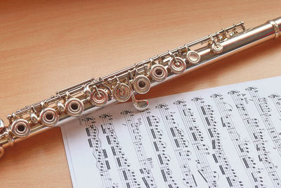High angle view of saxophone with sheet music on wooden table