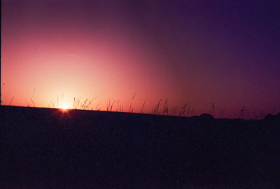 Scenic view of silhouette field against sky during sunset