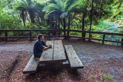 Man sitting on street amidst trees in forest