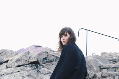 Portrait of woman by rocks against clear sky