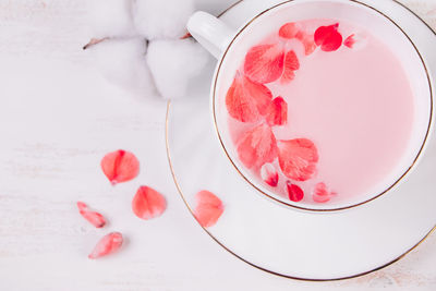 Trendy vegan tea on a white background. pink matcha with rose petals in a cup. relaxing drink recipe 
