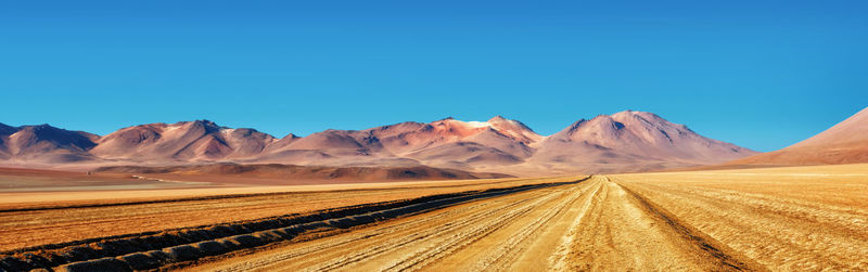 Scenic view of arid landscape against clear blue sky