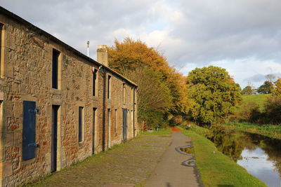 Footpath amidst trees and buildings against sky