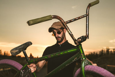 Portrait of man holding bicycle against sky