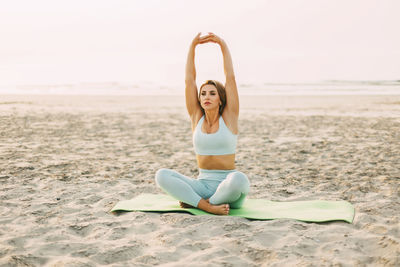 Full length of young woman sitting at beach