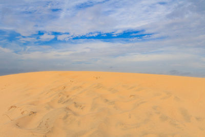 Scenic view of sand dunes against sky