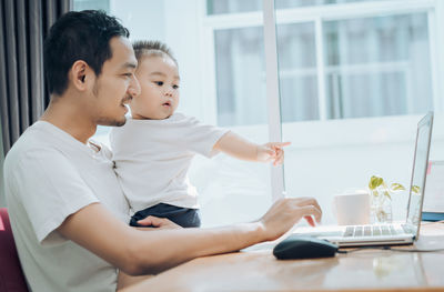 Mother and daughter using mobile phone while sitting on table