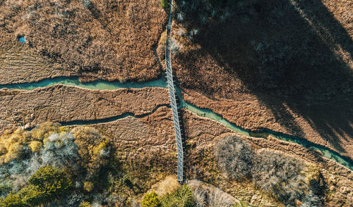 Amazing aerial view of footbridge over creek flowing through grassland