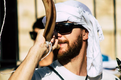 Portrait of young man holding sunglasses