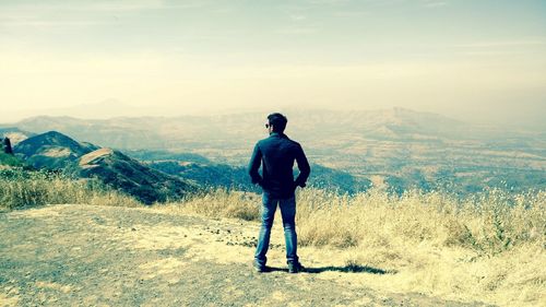 Rear view of man standing on landscape against sky