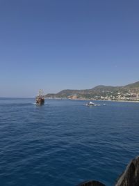 Sailboat in sea against clear blue sky