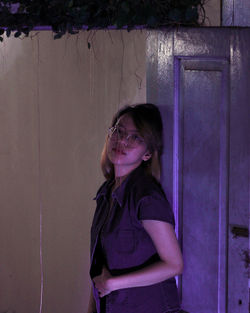 Portrait of woman standing against wall