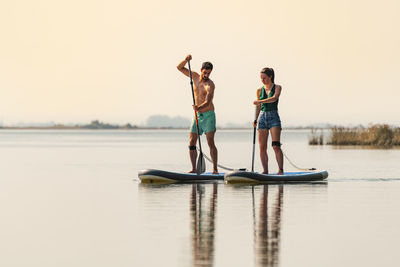 Full length of friends standing in lake against sky