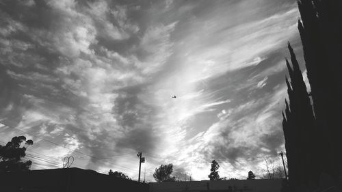 Low angle view of cloudy sky over silhouette landscape