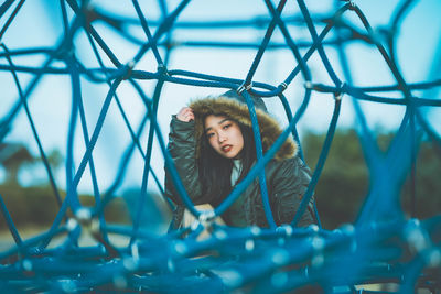 Portrait of beautiful young woman standing on metallic structure