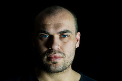 Portrait of serious man against black background