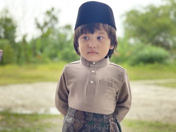 Portrait of cute boy standing on field celebrate eid fitr