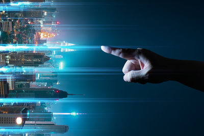 Digital composite image hand gesturing towards illuminated city