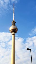 Low angle view of communications tower against cloudy sky