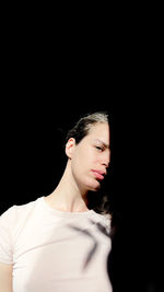 Portrait of a young woman looking away over black background