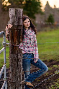 Young woman standing on barbed wire fence