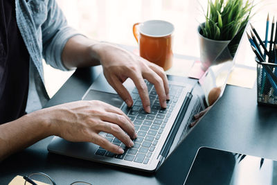 Midsection of man using laptop at table