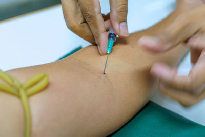 Cropped hand injecting syringe on patient hand