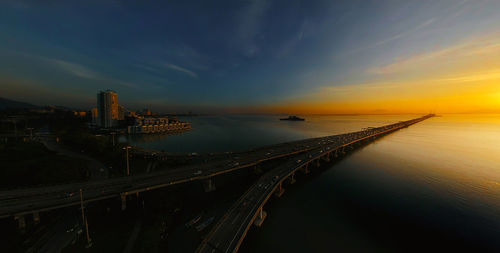 Aerial view of bridge over sea against sky during sunset