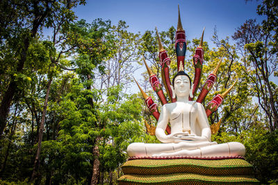 Low angle view of buddha statue against trees