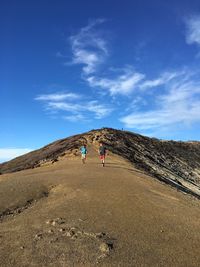 Men walking on mountain against blue sky