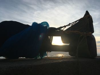 Side view of man sitting on land against sky