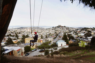 Man swinging over cityscape