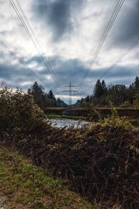 Electricity pylons on land against sky