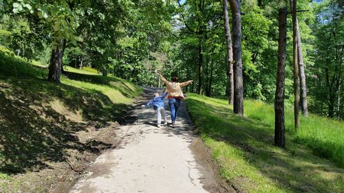 Rear view of people walking on footpath in forest