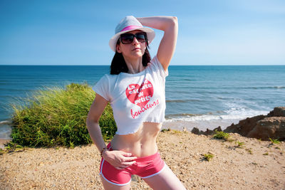 Young woman wearing sunglasses on beach against sky