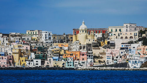 View of buildings by sea against blue sky