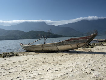 Fishing boats moored on beach against sky