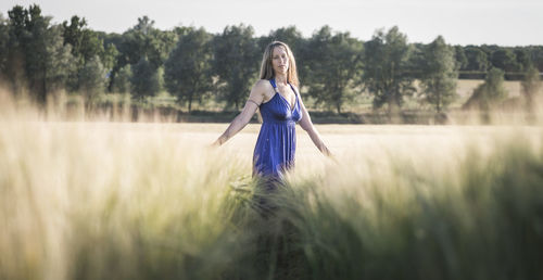 Portrait of woman walking on field against trees