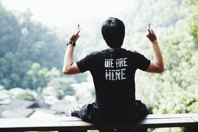 Rear view of boy with arms raised