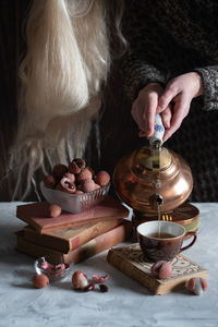 A woman pours tea from a copper teapot into a cup,still life with lychee,cozy