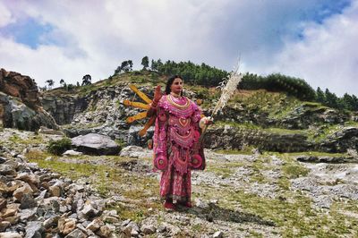 Woman standing on rock against sky