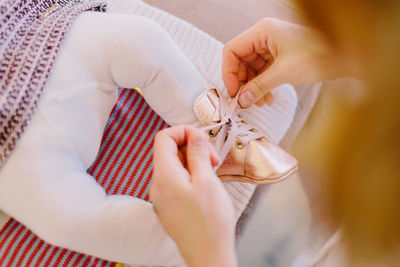 Close-up of mother typing shoelace of child