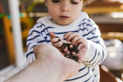 Mother's hand giving seed to boy standing at balcony