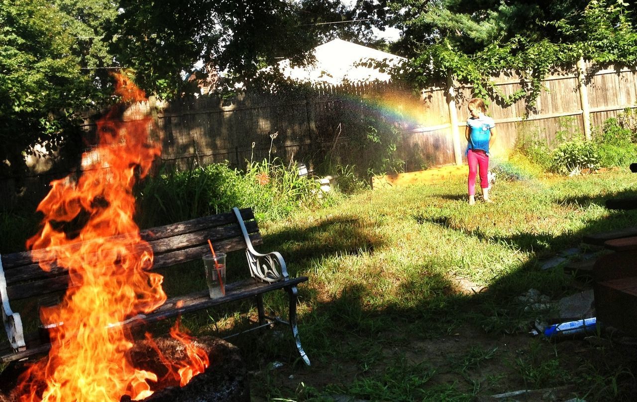 burning, flame, fire - natural phenomenon, heat - temperature, lifestyles, tree, men, fire, leisure activity, bonfire, outdoors, firewood, motion, smoke - physical structure, full length, grass, sunlight, field