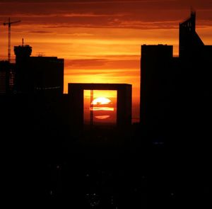 Silhouette houses against orange sky