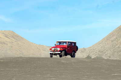 Vintage car on desert land against sky