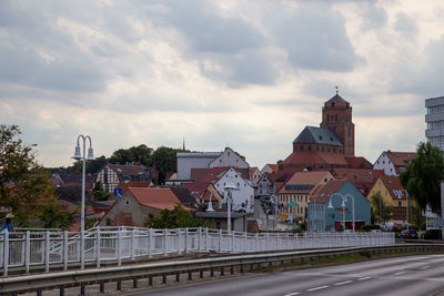 Road by buildings against sky in city