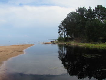 View of calm beach against cloudy sky