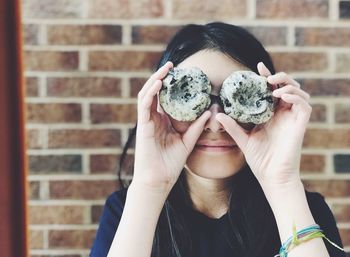 Girl holding cookies against wall